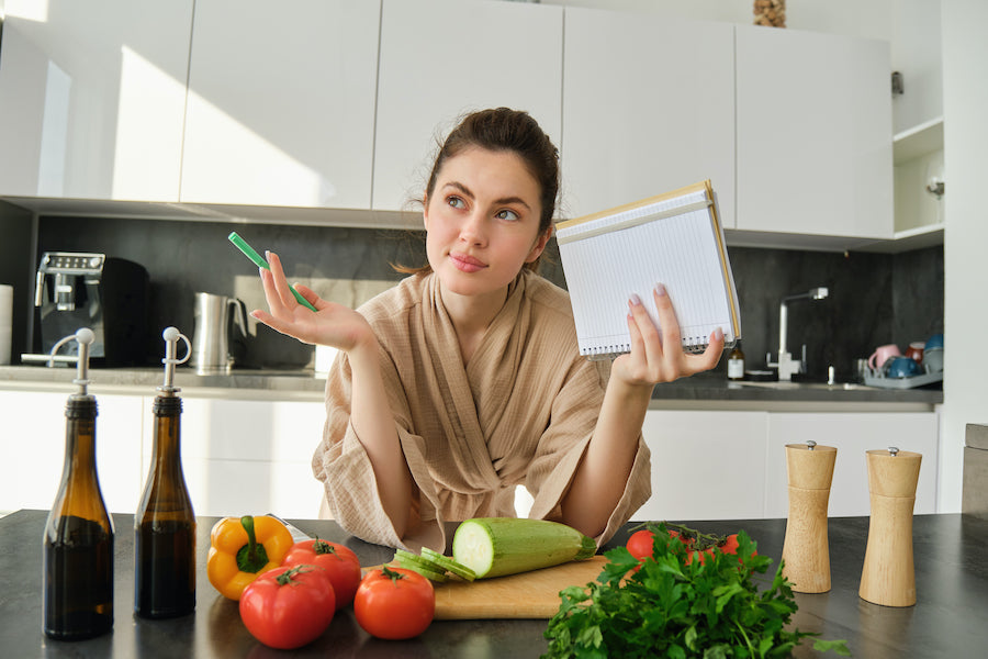 Persona en casa mirando comida saludable con expresión de duda al no ver resultados pese a cuidarse